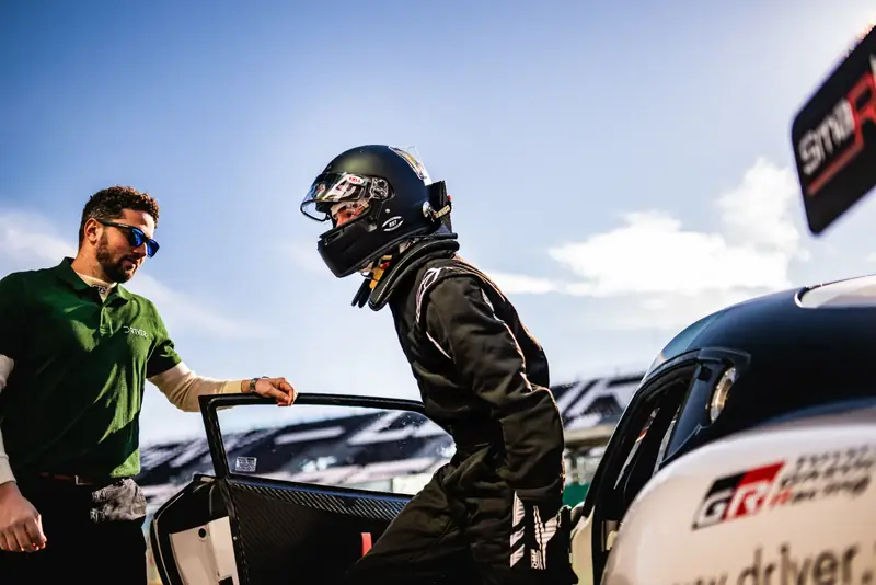 Instructeur Driver One accueillant un pilote équipé à la sortie de la voiture